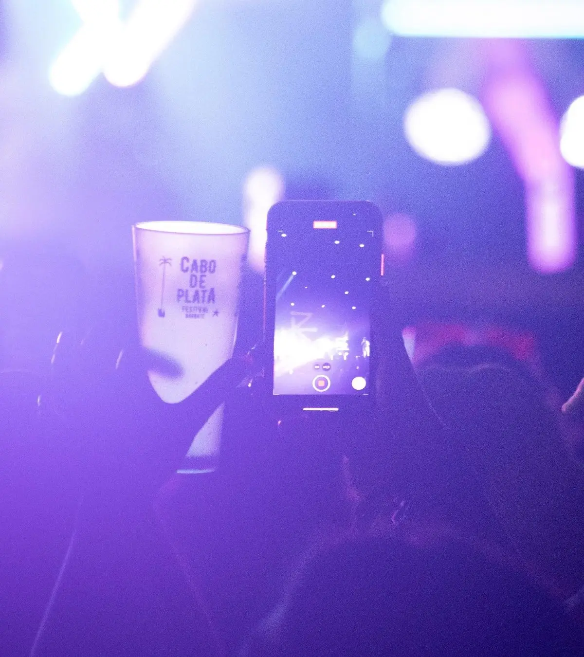 Público fotografiando un vaso personalizado en un concierto